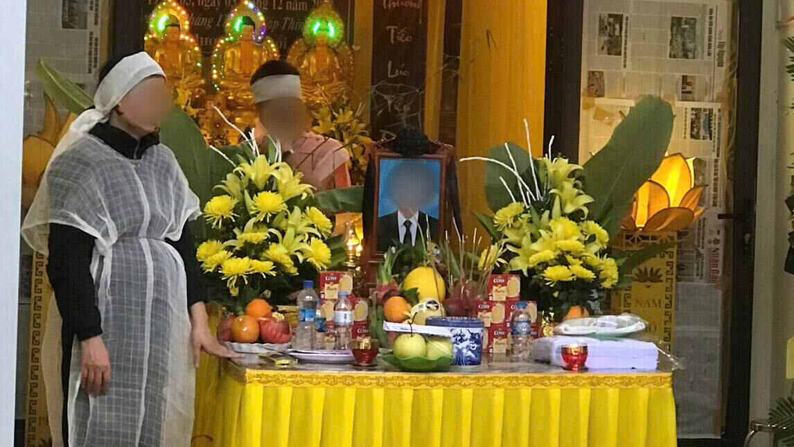 Hình ảnh người vợ xót xa đứng bên linh cữu của chồng. Ảnh: Yên San