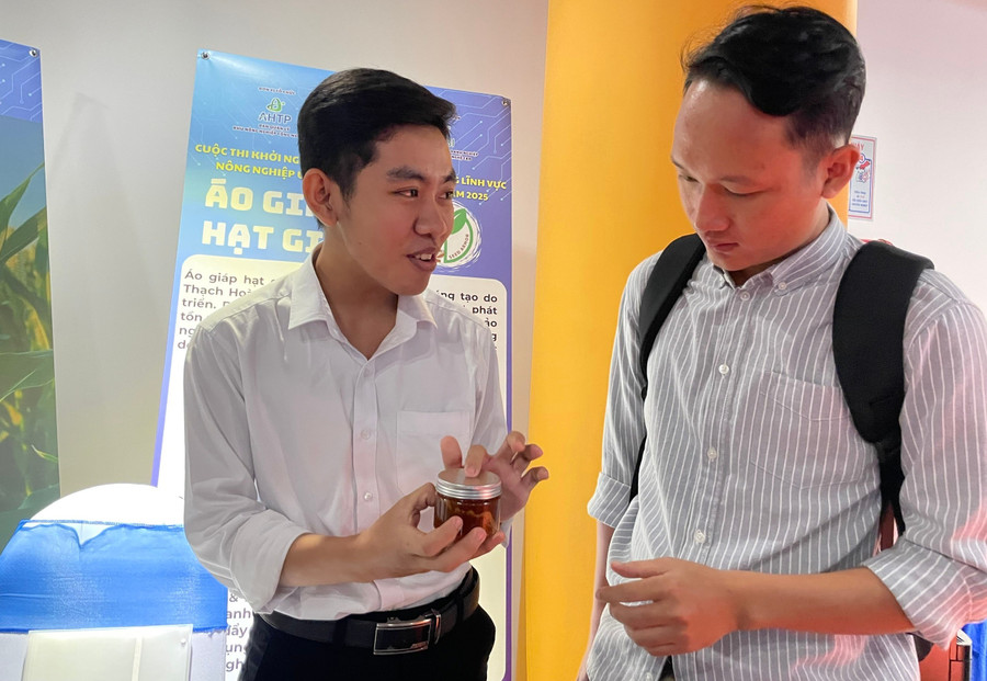 Thạch Hoàng Anh giới thiệu cho khách tham quan sản phẩm keo bảo vệ hạt giống cho mình nghiên cứu. Ảnh: Hà An