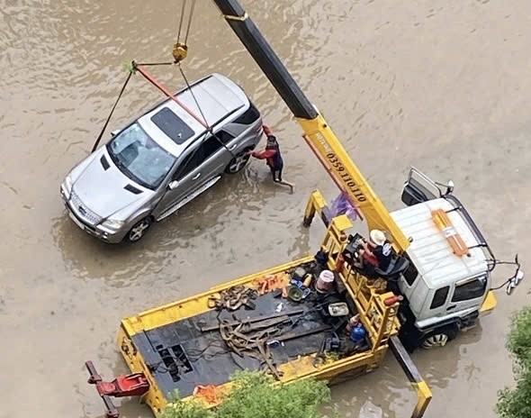 Xe ô tô bị ngập trong nước được xe cứu hộ cẩu lên